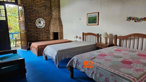 ein Schlafzimmer mit zwei Betten und einer Ziegelwand in der Unterkunft Casa de Meg Charme e Natureza na Serra Negra in Bezerros