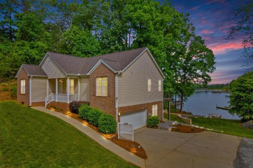 a house with a driveway in front of a lake at Castaway Cove -Lake Norman Waterfront Home with Private Dock in Denver