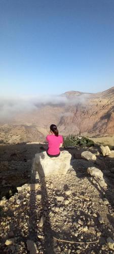 a woman sitting on a rock looking out over the mountains at Bedouins camp in Dana in At-Tafilah