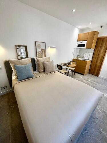 Cette chambre comprend un grand lit blanc et une cuisine. dans l'établissement La Petite Arlésienne, à Arles