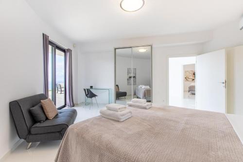 a white bedroom with a large bed and a chair at Villa Dione Palace in Falasarna
