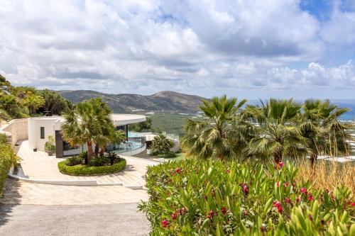 an exterior view of a house with palm trees and the ocean at Villa Dione Palace in Falasarna