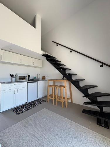 une cuisine avec des placards blancs et un escalier noir dans l'établissement Studio terrasse aperçu mer vignes, à Saint-Cyr-sur-Mer