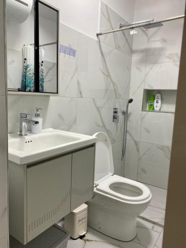 SeaScape APT في دوريس: حمام أبيض اللون مزود بحوض غسيل ومرحاض