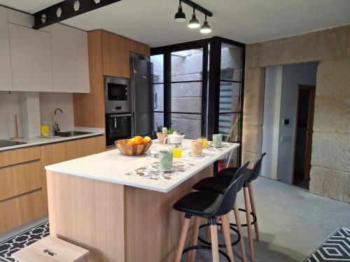 cocina con encimera con taburetes y mesa en Casa Ulloa, en Marín