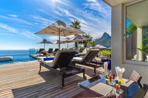 a deck with chairs and an umbrella and the ocean at Atlanticview Cape Town Boutique Hotel in Cape Town