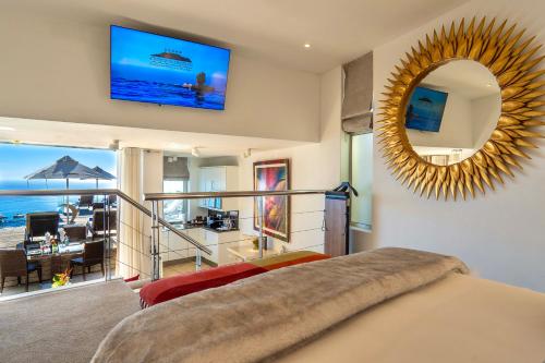 a bedroom with a large mirror and a living room at Atlanticview Cape Town Boutique Hotel in Cape Town