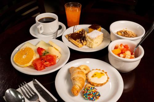 a table topped with plates of breakfast foods and coffee at Del Rey Quality Hotel in Foz do Iguaçu