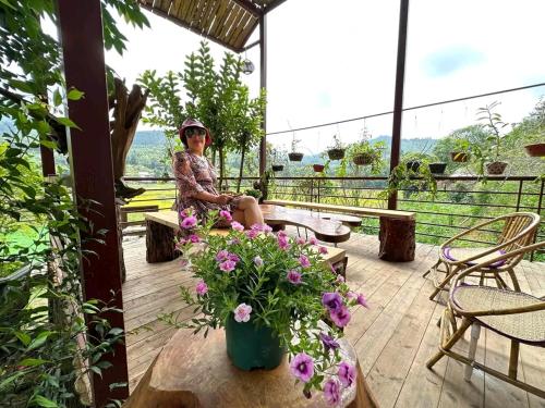 a woman sitting on a porch with flowers at Moc's House bắc hà in Bắc Hà