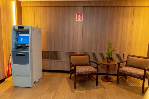 a waiting room with a television and chairs and a table at Del Rey Quality Hotel in Foz do Iguaçu