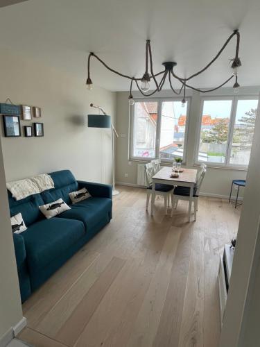 un salon avec un canapé bleu et une table dans l'établissement Le Bellevue Appartement, à Merlimont