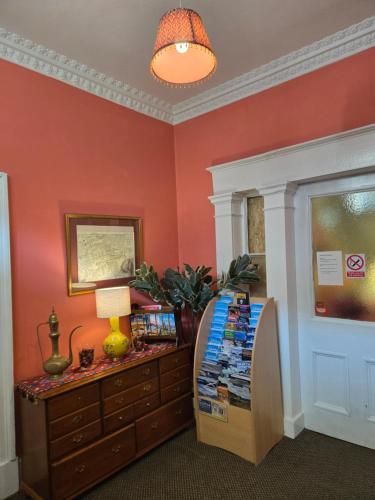 a room with red walls and a table with books at the CITY- Braveheart House in Edinburgh