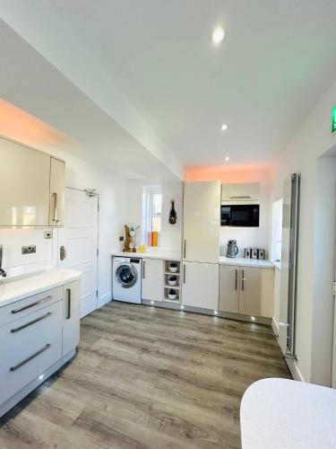 a large kitchen with white cabinets and a wooden floor at New - The Fun House Blackpool - Private nightclub in Blackpool