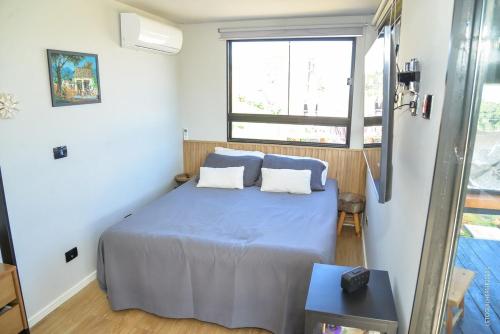a bedroom with a bed with blue sheets and a window at Container-house - Serra da Mantiqueira - MG in Toledo