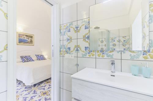 a bathroom with a bed and a sink and a mirror at Palazzo Trara - Holiday Rooms in Scala