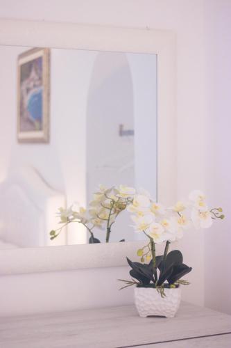 a vase with white flowers on a table in front of a mirror at Palazzo Trara - Holiday Rooms in Scala