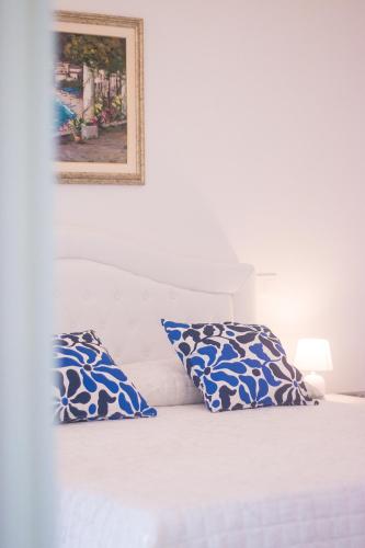 a bed with two blue and white pillows on it at Palazzo Trara - Holiday Rooms in Scala