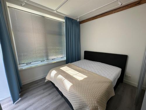 a small bedroom with a bed and a window at Golf course around the corner! in Nieuwveen