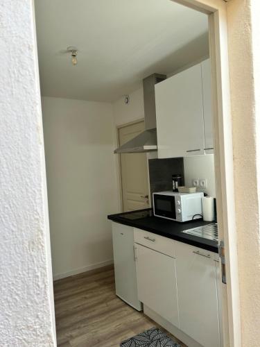 une cuisine avec des armoires blanches et un micro-ondes dans l'établissement Golden house près de gare, à Troyes