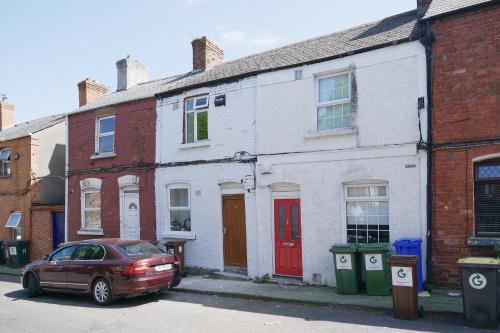 a red car parked in front of a white house at Cozy 2-Bedroom Detached Home No-7 in Dublin