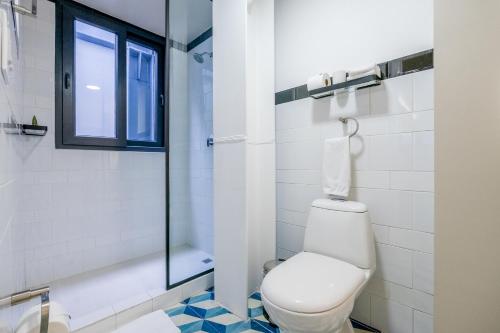 a bathroom with a toilet and a glass shower at La Manzana By Wynwood House in Paloma
