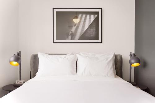 a bedroom with a bed with white sheets and two lamps at La Manzana By Wynwood House in Paloma