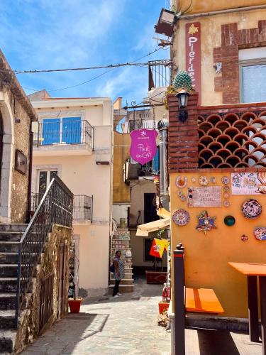 an alley with a building and a person walking down the street at Tyche House Castelmola in Castelmola