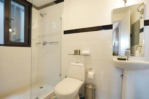 a white bathroom with a toilet and a sink at La Manzana By Wynwood House in Paloma