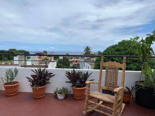 a rocking chair sitting on a balcony with plants at Casa La Maria Zona Colonial in Santo Domingo