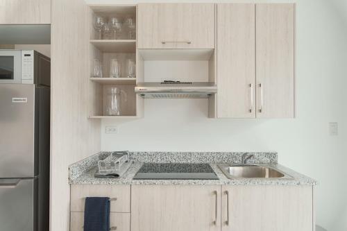 a white kitchen with a sink and a refrigerator at La Manzana By Wynwood House in Paloma