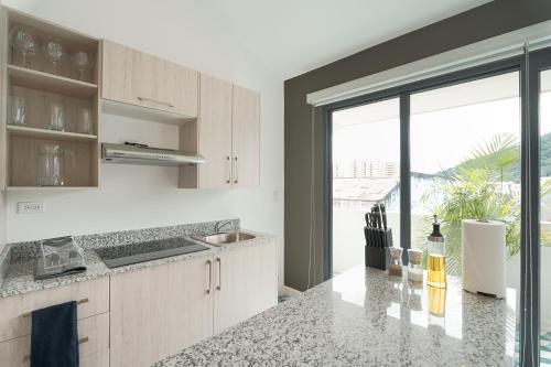 a kitchen with white cabinets and a large window at La Manzana By Wynwood House in Paloma