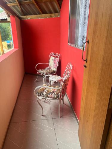 two chairs sitting in a room with red walls at Suites da Dorinha in Visconde De Maua