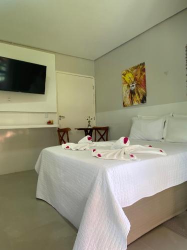 a bedroom with a bed with white sheets and a tv at Parada IT in Japaratinga