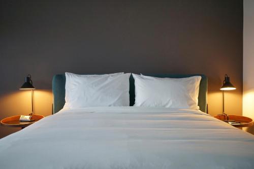 a bed with white sheets and pillows and two lamps at La Manzana By Wynwood House in Paloma