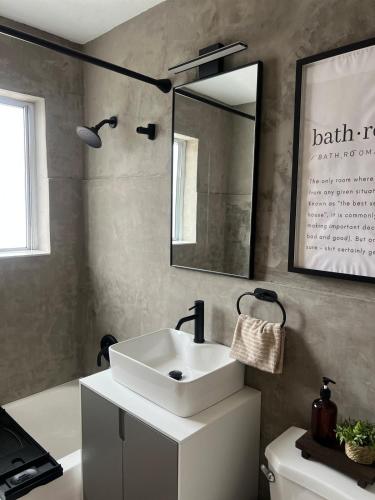 a bathroom with a sink and a mirror and a tub at Cozy Bohemian Apartment in Toronto