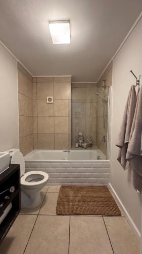 a bathroom with a tub and a toilet and a shower at Beachview Apartment in Hout Bay