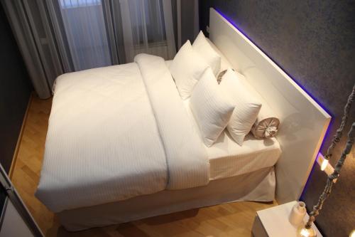 a bed with white sheets and pillows in a room at Maxela Apartments in Tbilisi City