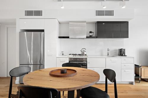 a kitchen with a wooden table and black chairs at Sleek City Flat, 5-Star Location with Free Parking in Melbourne