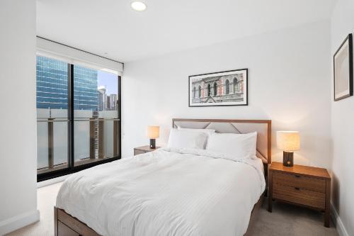 a white bedroom with a large bed and a window at Sleek City Flat, 5-Star Location with Free Parking in Melbourne