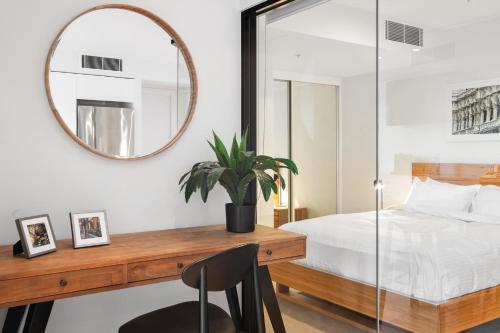 a bedroom with a bed and a mirror and a desk at Sleek City Flat, 5-Star Location with Free Parking in Melbourne