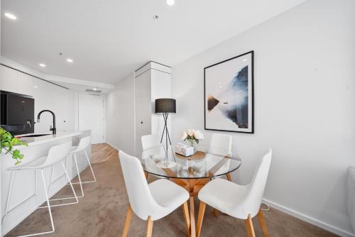 a dining room with a glass table and white chairs at Stylish 2-Bed Apartment in Canberra CBD in Canberra