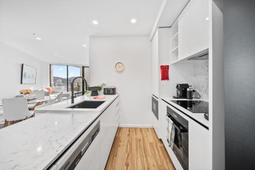 a white kitchen with white countertops and a sink at Stylish 2-Bed Apartment in Canberra CBD in Canberra