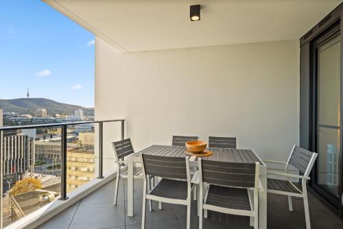 a dining room with a table and chairs on a balcony at Stylish 2-Bed Apartment in Canberra CBD in Canberra