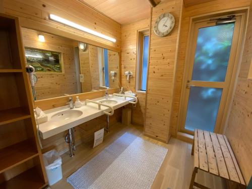 a bathroom with two sinks and a clock on the wall at ビジネスイン拝島 in Akishima