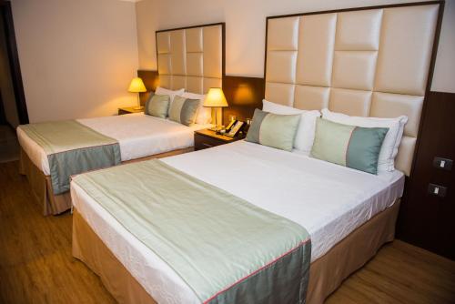 a hotel room with two beds and a telephone at Royal Atlântica Macaé Hotel in Macaé