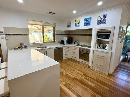 a large kitchen with white counter tops and wooden floors at South Bunbury Retreat in Bunbury