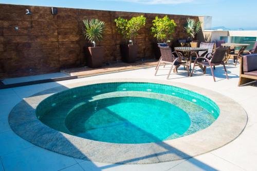 a swimming pool on a patio with a table and chairs at Royal Atlântica Macaé Hotel in Macaé