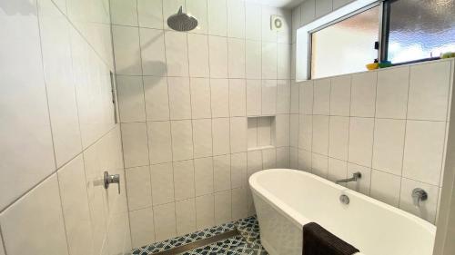 Un baño blanco con bañera y ventana. en Minnie Beach House, en Minnie Water