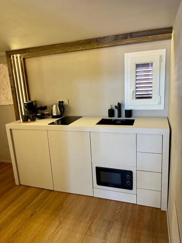 a white kitchen with a sink and a microwave at Renard Suite in Cefalù