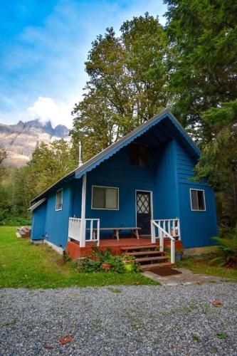 a blue house with a porch and stairs to it at Cozy cabin in the shadow of Mt Baring in Baring